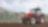  A red tractor ploughing a muddy field with trees in the background