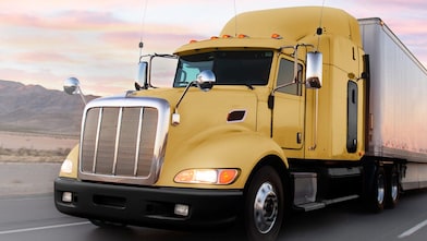 un camion giallo che procede lungo una strada al crepuscolo