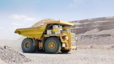 Yellow dumper truck driving through gravel