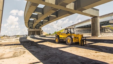 A yellow truck driving down a road at dusk