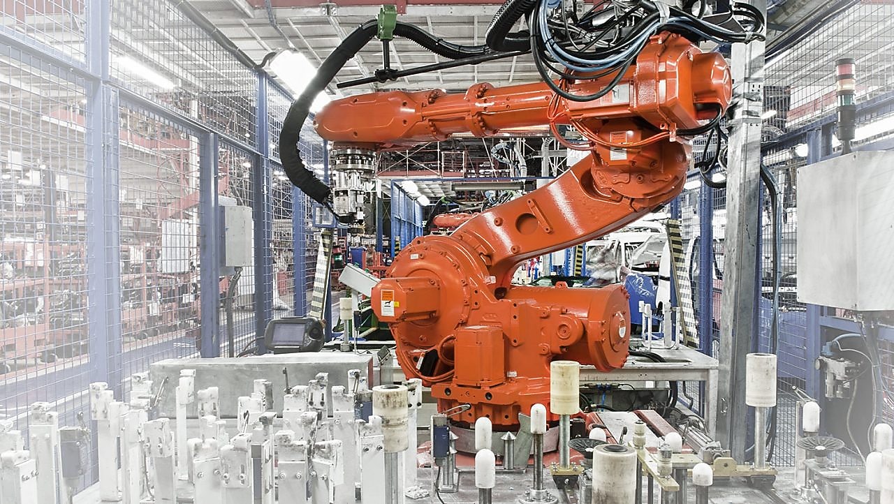 A red robotic arm in a factory