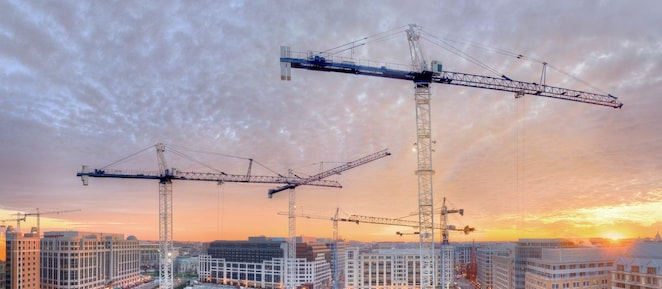 Three cranes on a building site at dusk