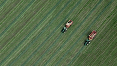 Two tractors in a green field pictured from above