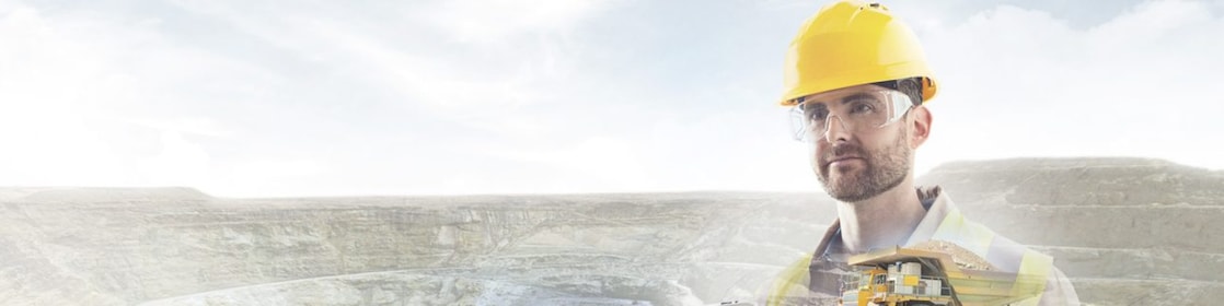 worker in yellow hard hat transposed onto a background of cliffs and a large yellow truck