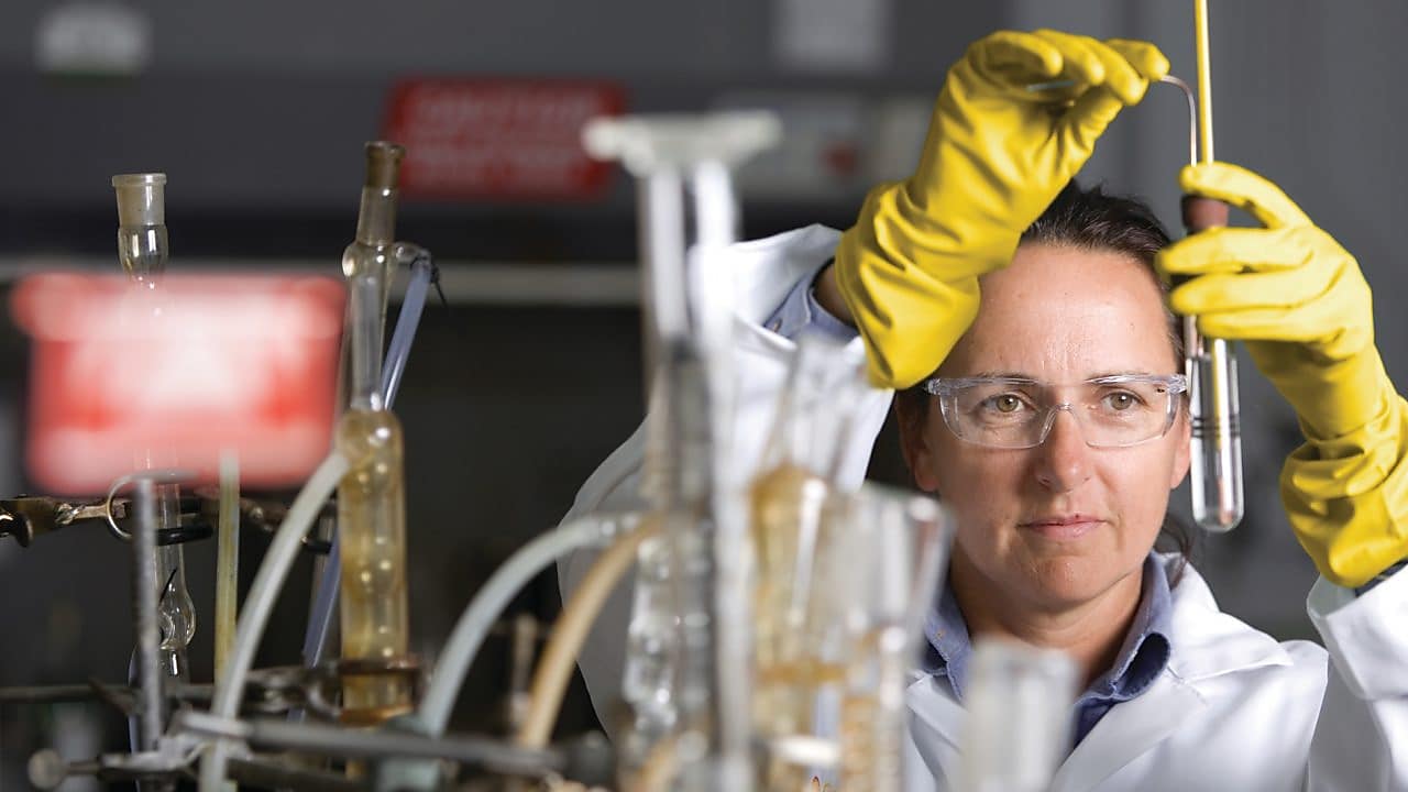 lady in safety goggles conducting a lab experiment