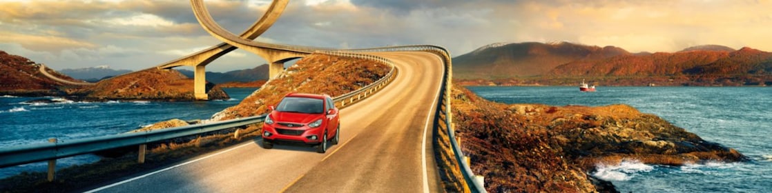 Red car driving on the road by the river