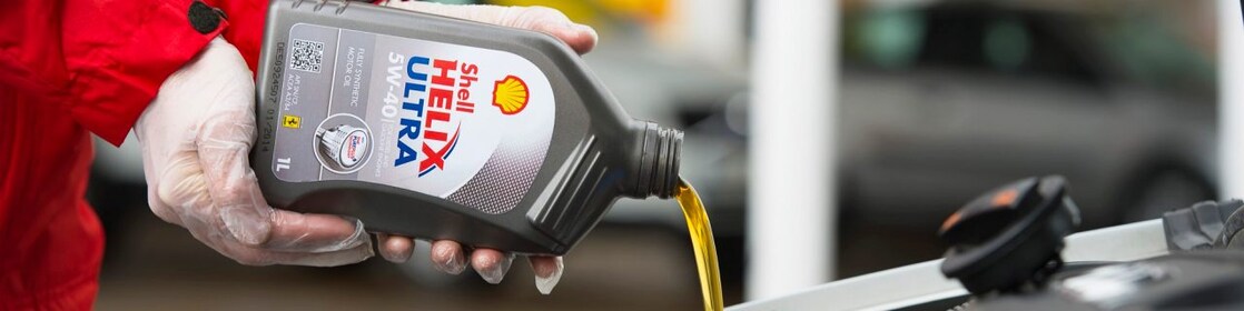 Man filling shell helix ultra oil in car