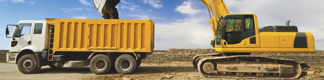 yellow excavator loading mud into a truck