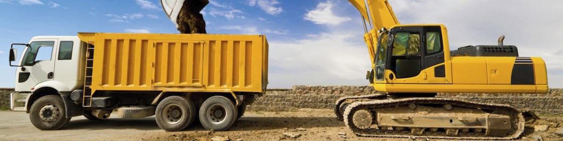 yellow excavator loading mud into a truck